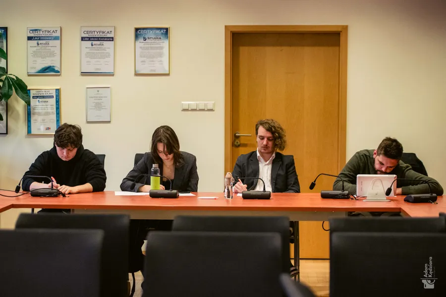 Czteroosobowy skład przygotowuje się do mowy przy stole z mikrofonami